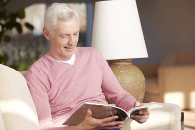 Kanepede kitap okuyan adam.