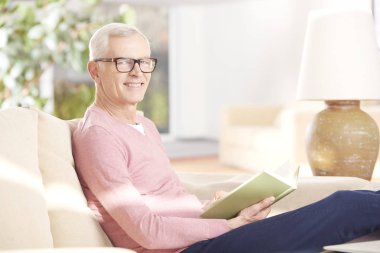 Kanepede kitap okuyan adam.