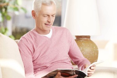 Kanepede kitap okuyan adam.