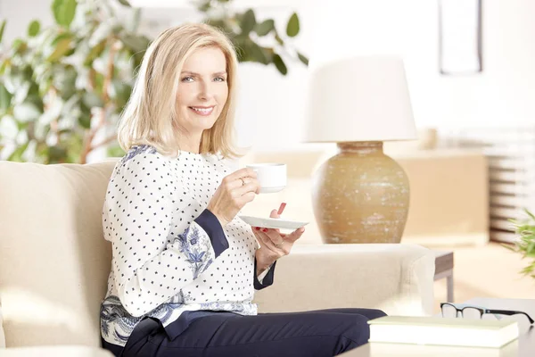 Lächelnde Frau trinkt Tee zu Hause — Stockfoto
