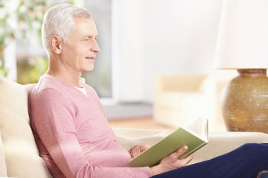 Son sınıf öğrencisi evde kitap okuyor. 