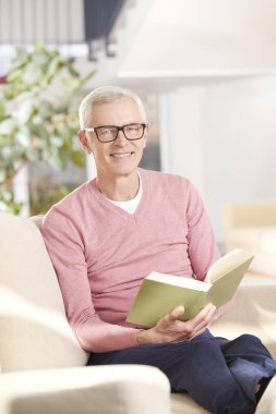 Son sınıf öğrencisi evde kitap okuyor. 