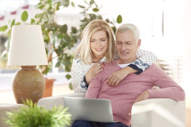 Evde dizüstü bilgisayar kullanan yaşlı bir çift.