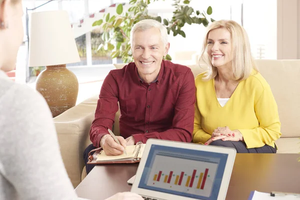 Elderly couple sitting at home with adviser — Stock Photo, Image