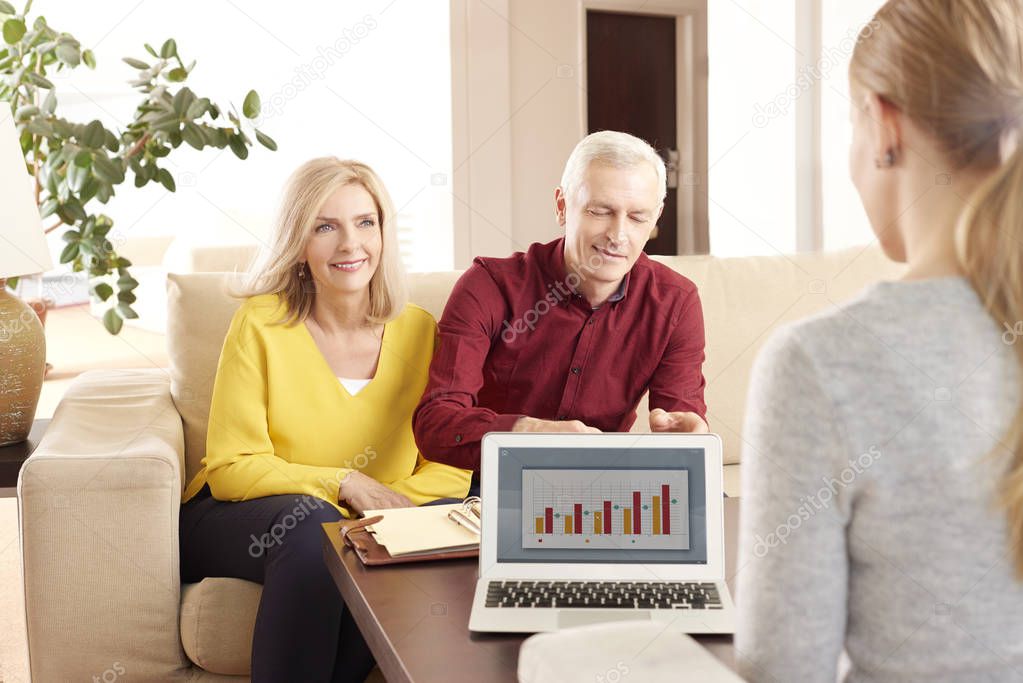 elderly couple sitting at home with adviser