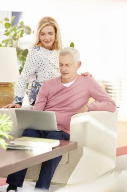 Evde dizüstü bilgisayar kullanan yaşlı çift.