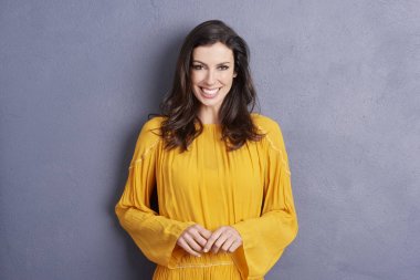 gri duvarın karşısında dururken gülümseyen kadın