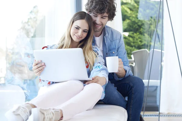 Couple relaxing on couch with laptop — Stock Photo, Image