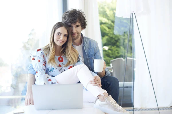 couple sitting on couch with laptop