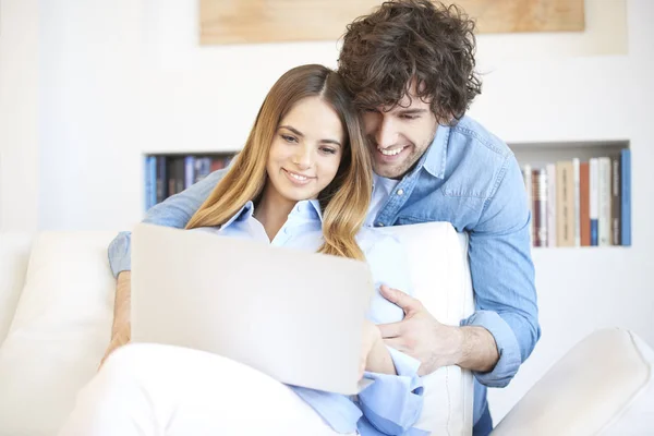 Pareja sentada en el sofá con portátil — Foto de Stock