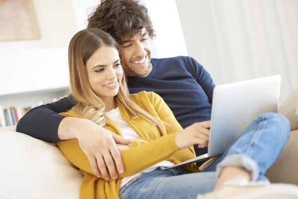 Couple on couch and using laptop — Stock Photo, Image
