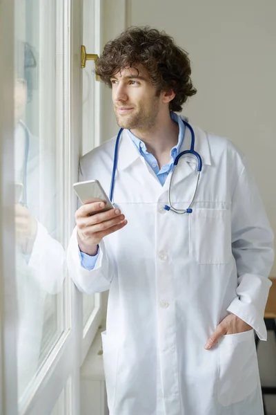 Lékař používá svůj mobilní telefon — Stock fotografie