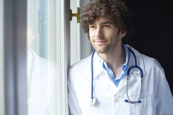 Jonge dokter permanent ter venster. — Stockfoto