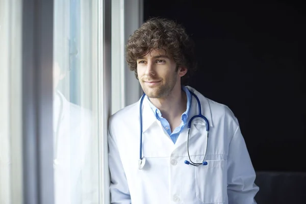 Νεαρός γιατρός στέκεται στο παράθυρο. — Φωτογραφία Αρχείου