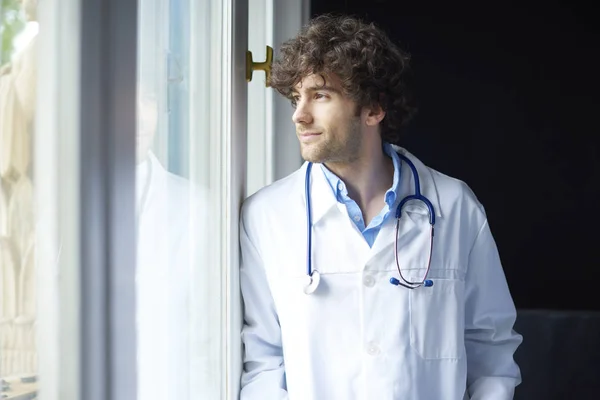 Νεαρός γιατρός στέκεται στο παράθυρο. — Φωτογραφία Αρχείου