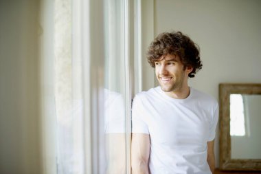 gülümseyen rahat genç adam üstünde belgili tanımlık pencere bakan