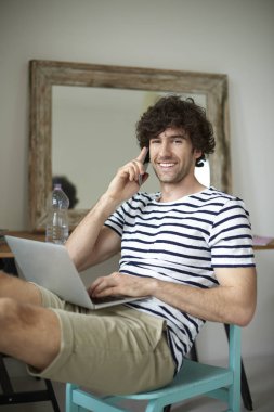 Mutlu genç adam cep telefonu ve dizüstü 