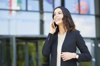 Genç iş kadını cep telefonunu kullanıyor.