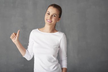 Başparmak gösteren genç bir kadın.