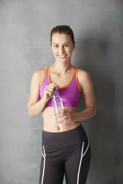 Mujer sonriente sosteniendo botella de agua — Foto de Stock