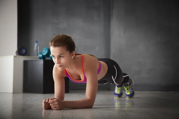 Vrouw doen plank oefening op sportschool — Stockfoto