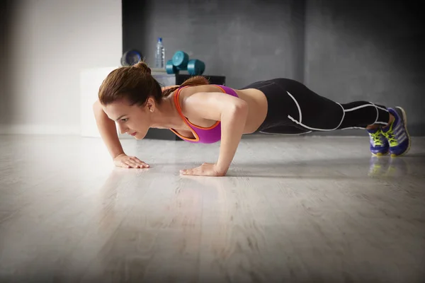 Vrouw doen plank oefening op sportschool — Stockfoto