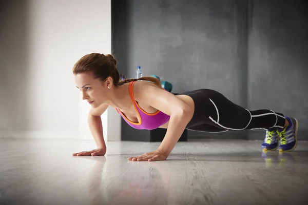 Mujer haciendo push up en el gimnasio — Foto de Stock