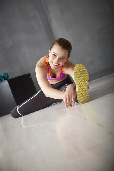 Mujer joven estiramiento piernas — Foto de Stock