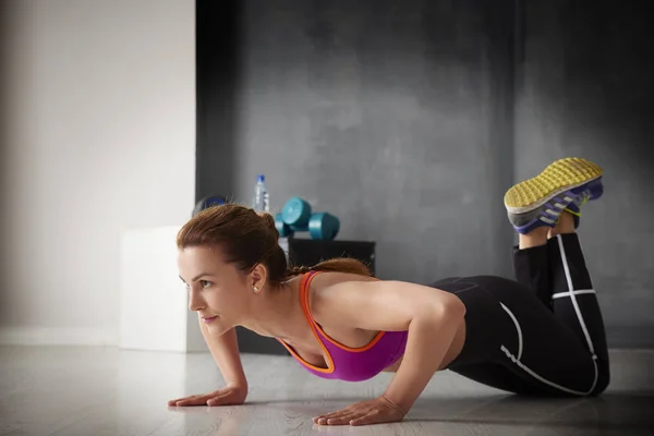 Jonge vrouw doet push-ups — Stockfoto