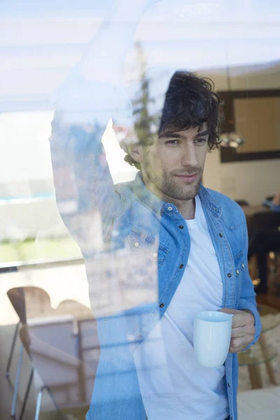 Hombre Joven Guapo Mirando Pensativamente Mientras Está Pie Ventana Beber —  Fotos de Stock