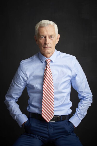 Shot of an executive senior man wearin shirt and tie at black wall