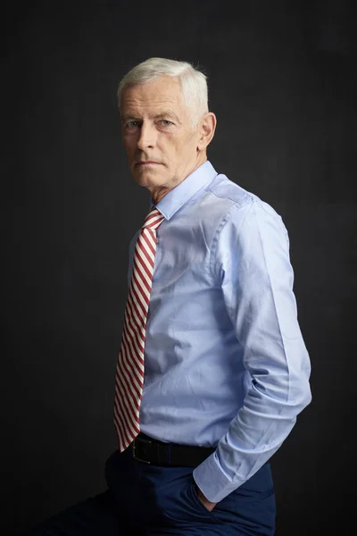 Executive senior man wearing shirt and tie before black wall