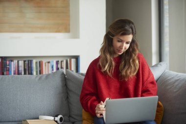 Onu rahat kanepe online bankacılık sırasında kredi kartı ve dizüstü bilgisayar kullanan güzel orta yaşlı kadın.