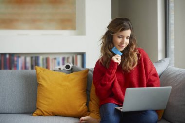 Onu rahat kanepe online bankacılık sırasında kredi kartı ve dizüstü bilgisayar kullanan güzel orta yaşlı kadın.