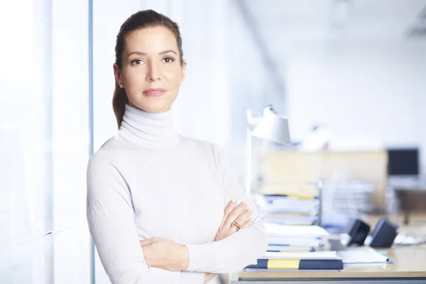 Executive sales businesswoman standing at the office with arms crossed and looking at camera.