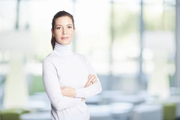 Executive sales businesswoman standing at the office with arms crossed and looking at camera.