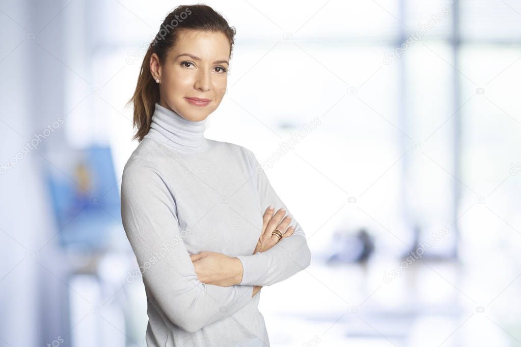 Executive sales businesswoman standing at the office with arms crossed and looking at camera.