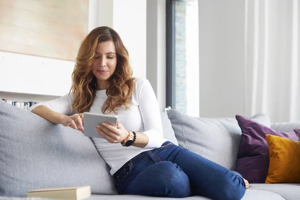 Sorrindo Mulher Meia Idade Usando Tablet Digital Enquanto Relaxa Sofá — Fotografia de Stock