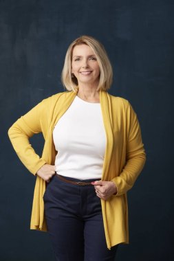 Kameraya bakarak ve duran koyu arka plan, gülümseyen çekici yaşlı kadın. 