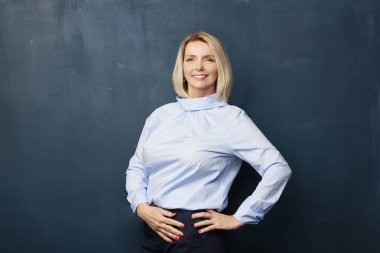 Süre ayakta, koyu arka plan ve gülümseyen gömlek giymiş güzel bir üst düzey kadının yakın çekim studio vurdu. 