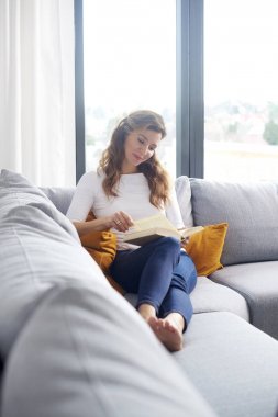 Güzel orta yaşlı kadın evde iyi bir kitap okuma.