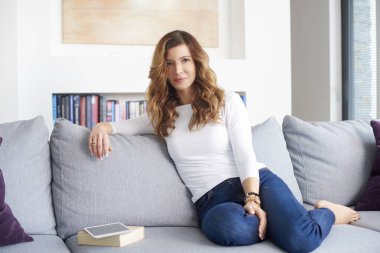 Olgun kadın ev onun modern rahat bir kanepede uyuklayan gülümseyen.