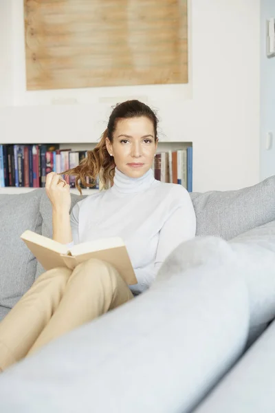 Mooie Lachende Rijpe Vrouw Zit Bank Leesboek Thuis — Stockfoto