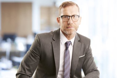 Ofiste oturan ve kameraya bakarak profesyonel komisyoncu işadamı orta yaşlı.