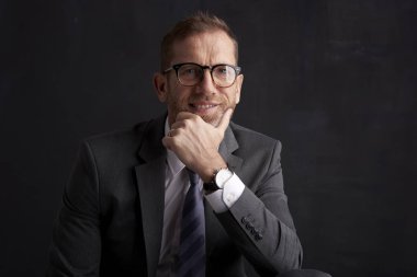 Takım elbise ve düşünceli arıyorum koyu arka plan otururken çenesini buruşuk yüz işadamı ile stüdyo çekim ver. Takım elbise ve kravat giyen profesyonel adam. 