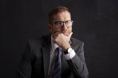 Takım elbise ve düşünceli arıyorum koyu arka plan otururken çenesini buruşuk yüz işadamı ile stüdyo çekim ver. Takım elbise ve kravat giyen profesyonel adam. 