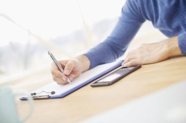 Businessmans el somesthing kağıda yazı close-up. Resepsiyon ve dolgu formu oturan rahat profesyonel adam. Ön plan üzerinde odaklanmak. 