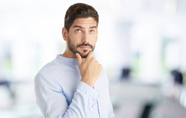 Yakışıklı bir genç adam ayakta ve thoughful seyir çene üzerinde el ile portre çekim.