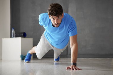 Spor salonunda bir bir elle itme yapıyor bir genç adam tam uzunlukta atış. 