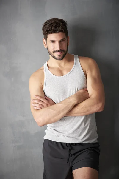 Three quarter length of young male personal trainer standing with crossed arms